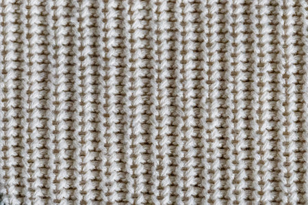 White knit wool fabric as a background. Wool knit texture. Knitted fabric surface with soft folds....