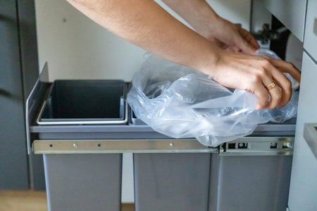 A housewife fodling a garbage bin in kitchen with a garbage bag. Waste separation conceptの写真素材