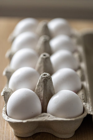 Open egg box with ten white eggs on wooden table. Fresh organic chicken eggs in carton pack or egg...