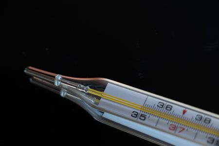 Old glass thermometer on a dark isolated background close-up