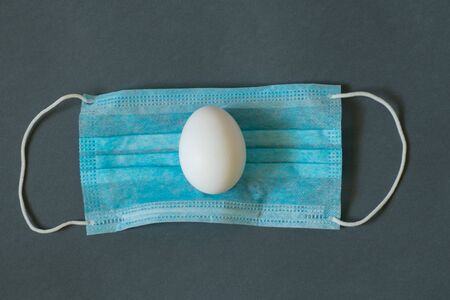 egg lies on a medical mask on an isolated backgroundの写真素材