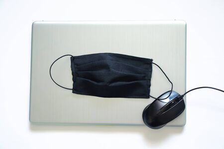 black medical mask and laptop, quarantine workの写真素材