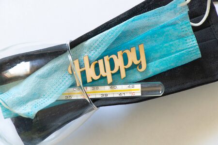 glass thermometer and the word happiness made of wood in a glass with a mask on a darkの写真素材