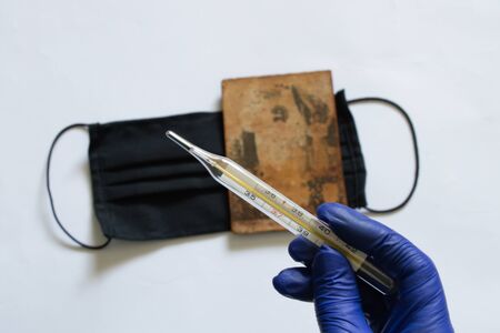 glass thermometer and hand in blue glove on the background of the Medetsyn mask