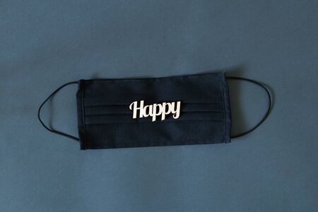 word happiness made of wood lies on a medical mask on an isolated background