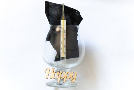 glass thermometer and the word happiness made of wood in a glass with a mask on a darkの写真素材