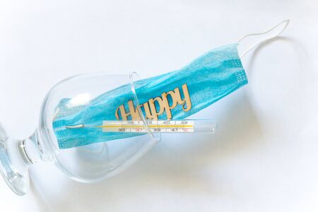 glass thermometer and the word happiness made of wood in a glass with a mask on a darkの写真素材