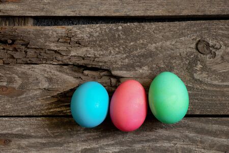 Easter dinner, colored chicken eggs on an old wooden table in the evening