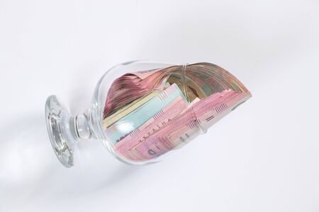 hryvnia and dollar lie in a glass cup on a white background
