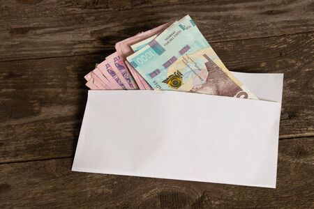 Ukrainian cash currency lies in a white envelope on an wooden table, salary in an envelope
