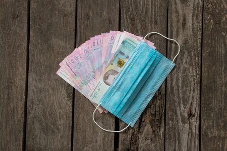 cash dollars and hryvnias and a medical mask
