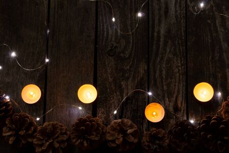 Christmas decor on a wooden board as a fonds with a garland and Christmas conesの写真素材