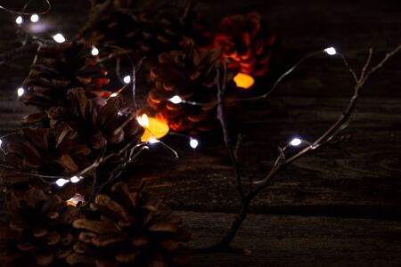 Christmas decor on a wooden board as a fonds with a garland and Christmas conesの写真素材