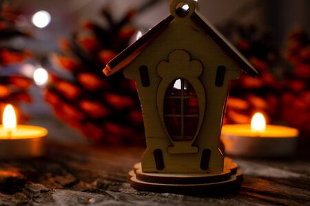wooden house as a Christmas decor and a garland on a wooden table and candles, New Yearの写真素材