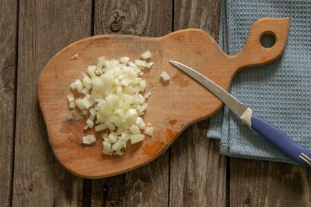 chopped onion lies on a wooden board on a tableの写真素材