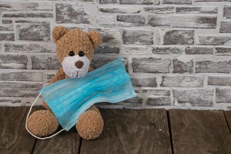 baby brown teddy bear and medical mask during a pandemicの写真素材