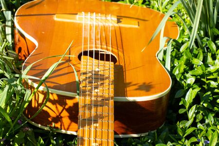 wooden brown guitar lies on the grass in spring in the sunの写真素材