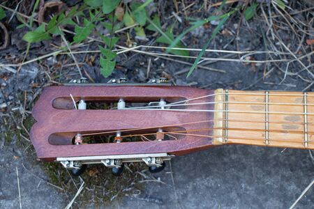 wooden brown guitar lies on a stone road in the street in the spring grassの写真素材