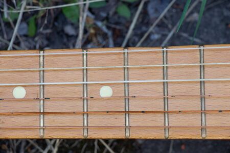 wooden brown guitar lies on a stone road in the street in the spring grass