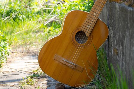 wooden brown guitar lies on a stone road in the street in the spring grassの写真素材