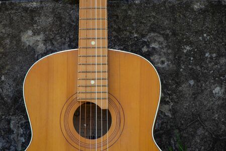 wooden brown guitar lies on a stone road in the street in the spring grassの写真素材