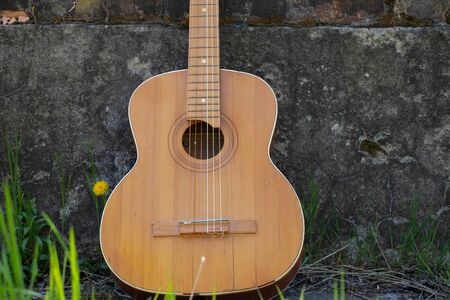 wooden brown guitar lies on a stone road in the street in the spring grassの写真素材