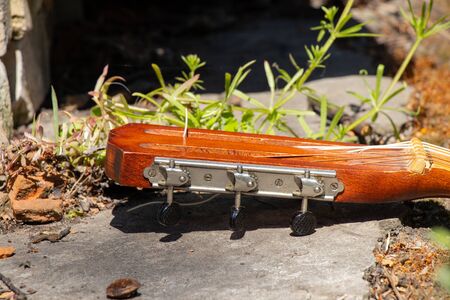wooden brown guitar lies on a stone road in the street in the spring grass in Ukraineの写真素材