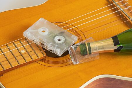 guitar and film cassette on an isolated background a bottle and a glassの写真素材