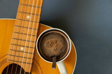 wooden guitar and a cup of coffee on a dark backgroundの写真素材