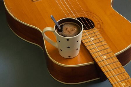 wooden guitar and a cup of coffee on a dark background