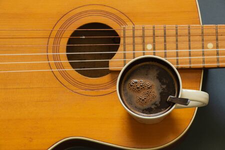 wooden guitar and a cup of coffee on a dark background