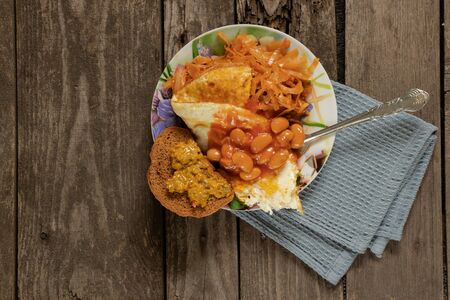 morning vegan breakfast fried scrambled eggs with cabbage and beans on a tableの写真素材