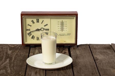 glass of milk and clock on a wooden tableの写真素材