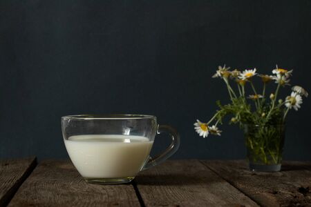 glass of milk and wild daisies on a table in the morningの写真素材