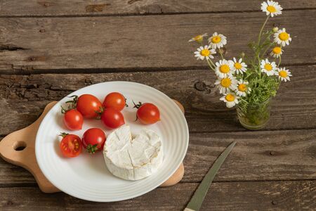 soft brie cheese and cherry tomatoes on a tableの写真素材