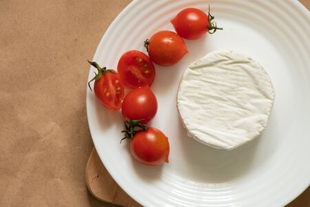 soft brie cheese lies and cherry tomatoes on a table