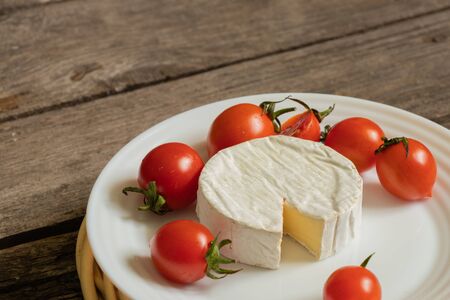 soft brie cheese and cherry tomatoes on a tableの写真素材