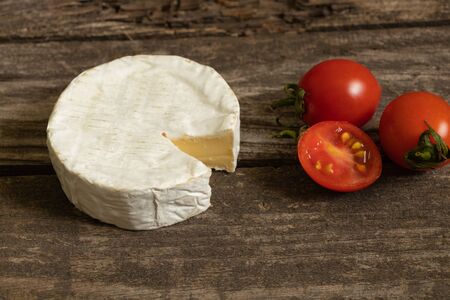 soft brie cheese and cherry tomatoes on a tableの写真素材