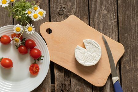 soft brie cheese and cherry tomatoes on a tableの写真素材