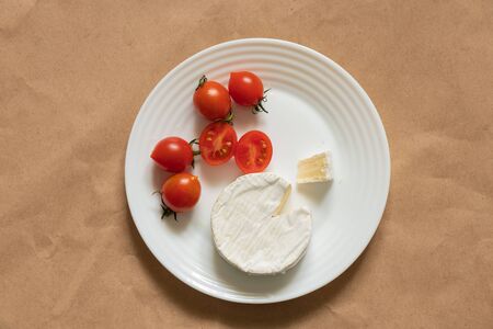 soft brie cheese lies and cherry tomatoes on a tableの写真素材