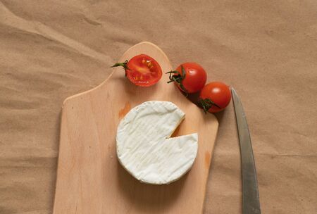 soft brie cheese lies and cherry tomatoes on a tableの写真素材