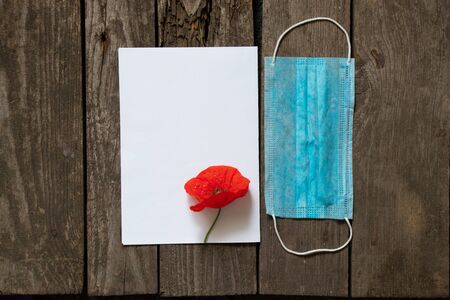 medical mask and poppy flower on the table and a white piece of paperの写真素材
