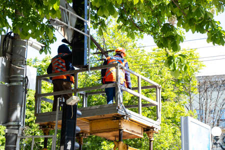 Ukraine, Dnipro - May 14, 2020.Two people are repairing traffic lights near the road on a crane to the cities of Dnieper in Ukraineのeditorial素材