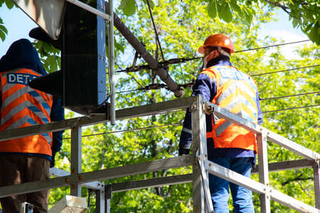 Ukraine, Dnipro - May 14, 2020.Two people are repairing traffic lights near the road on a crane to the cities of Dnieper in Ukraineのeditorial素材