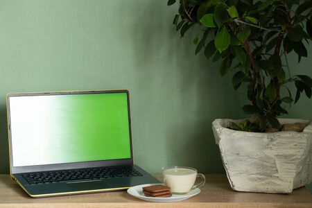 laptop with green screen yogurt with cookies on a table in a room at homeの写真素材