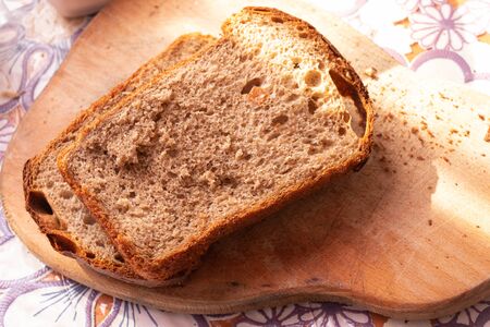 brown bread lies on a wooden board on a tableの写真素材