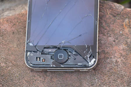 Ukraine, Dnipro - April 03, 2020. An old broken iPhone 4 lies on a stone.Ukraine, Dnipro - April 03,...
