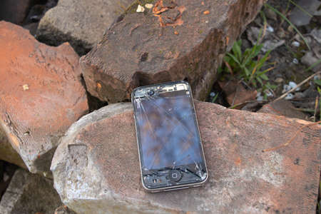Ukraine, Dnipro - April 03, 2020. An old broken iPhone 4 lies on a stone.Ukraine, Dnipro - April 03,...