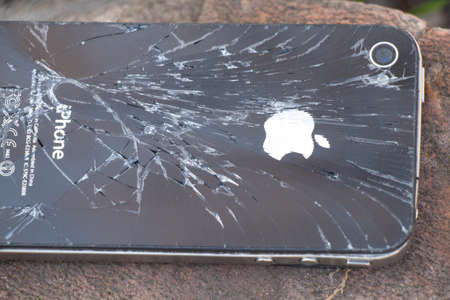 Ukraine, Dnipro - April 03, 2020. An old broken iPhone 4 lies on a stone.Ukraine, Dnipro - April 03, 2020. An old broken iPhone 4 lies on a stone close-up.のeditorial素材