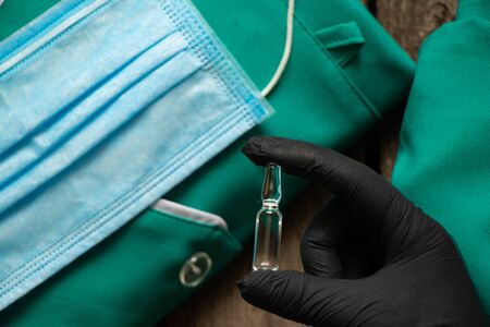 hand in gloves holds an ampoule with medicineの写真素材